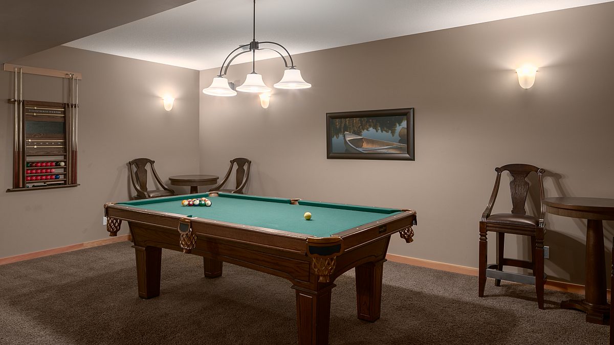 Recreation room with pool table, overhead lighting and seating areas.