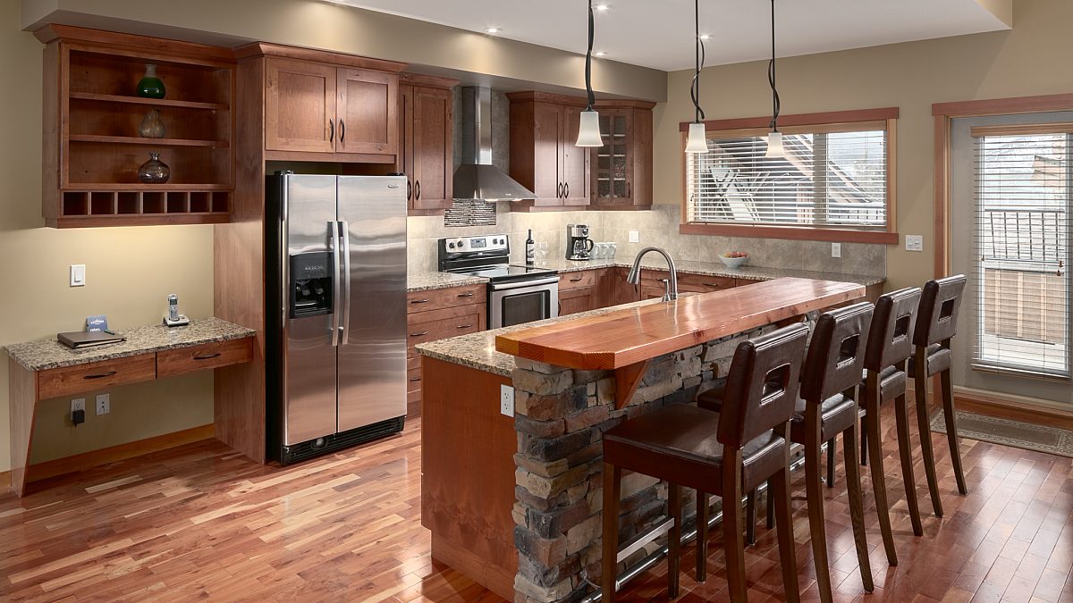 Spacious kitchen with island, four barstools and appliances.