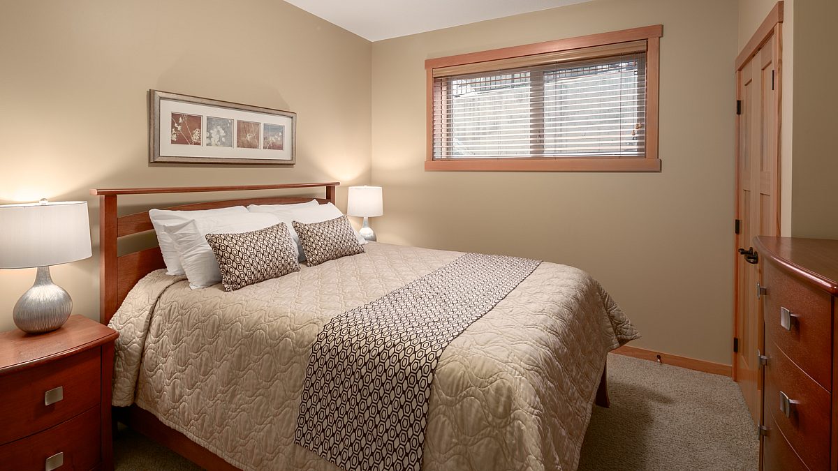 Queen bedroom with taupe bedding and window to the right.