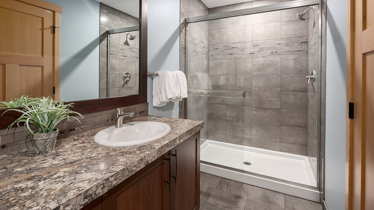 Ensuite bathroom with large shower area, sink, and mirror.