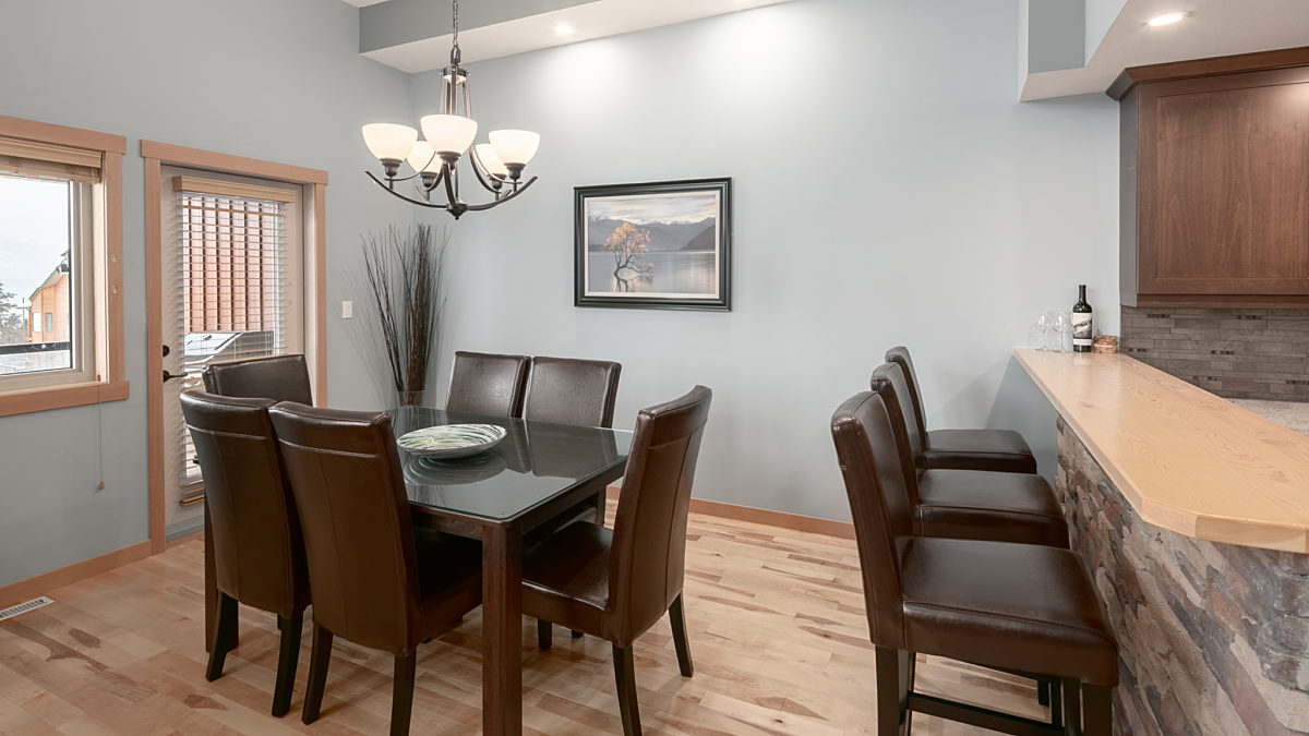 Dining room area with kitchen table and chairs. Overhead lighting above.