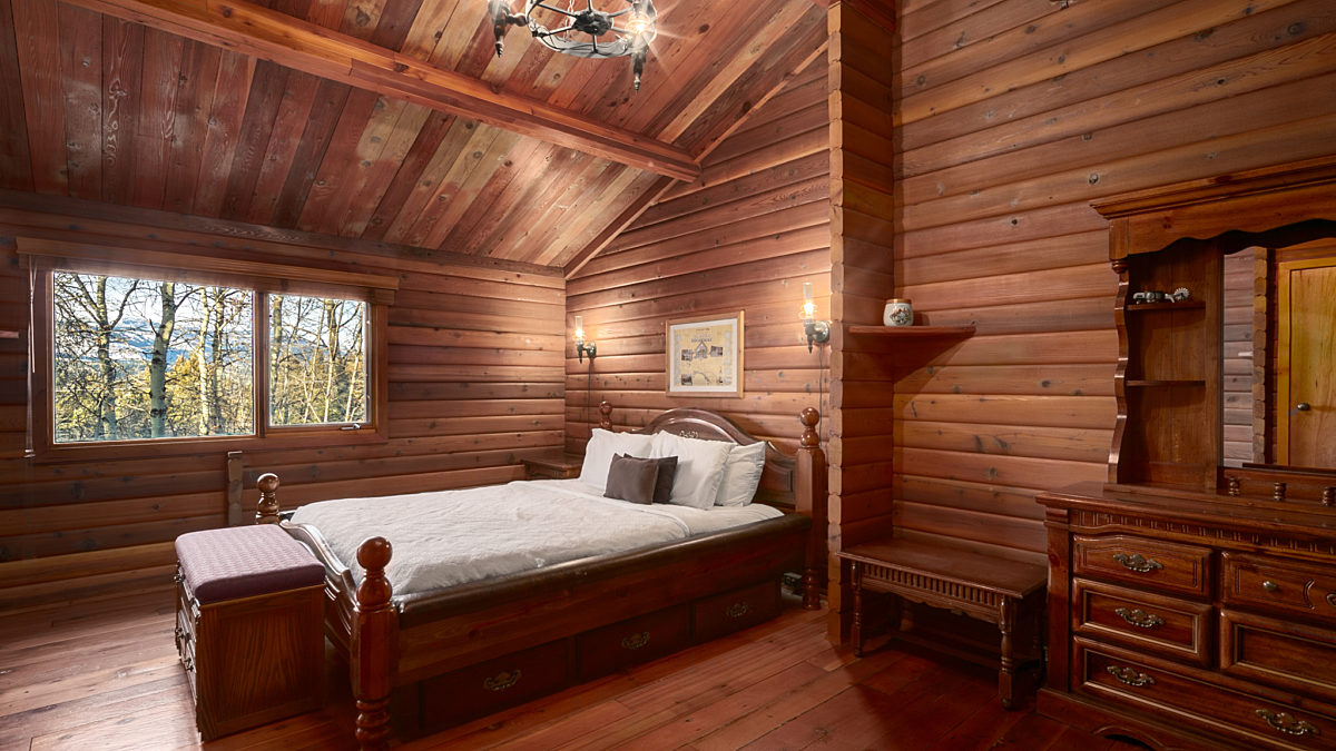 Master bedroom with king bed. Rustic interior with wood panelling.