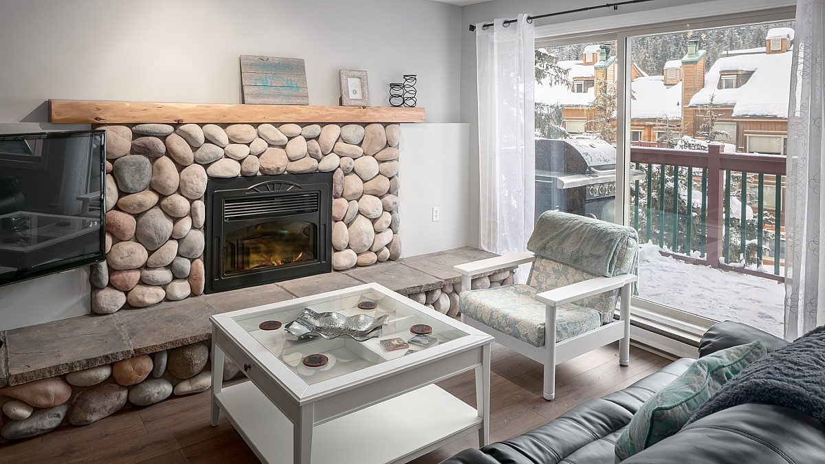 Rock fireplace with seating area, chairs, and couches. Glass doors to the right leading to patio.