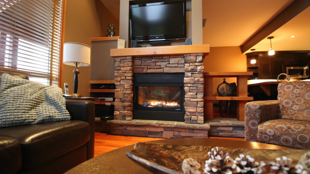 Stone fireplace with television mounted on top. Seating area and couches nearby.