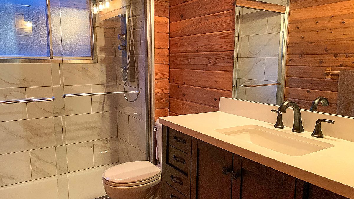Bathroom with wood panelling, shower, sink, and toliet.