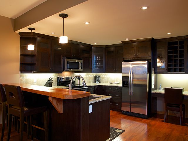 Kitchen with black cabinets, stainless steel fridge, kitchen island, and appliances.