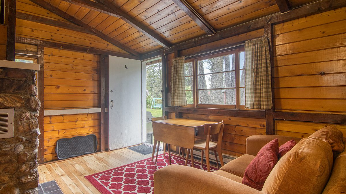 Living and dining area in wood panelled cabin.