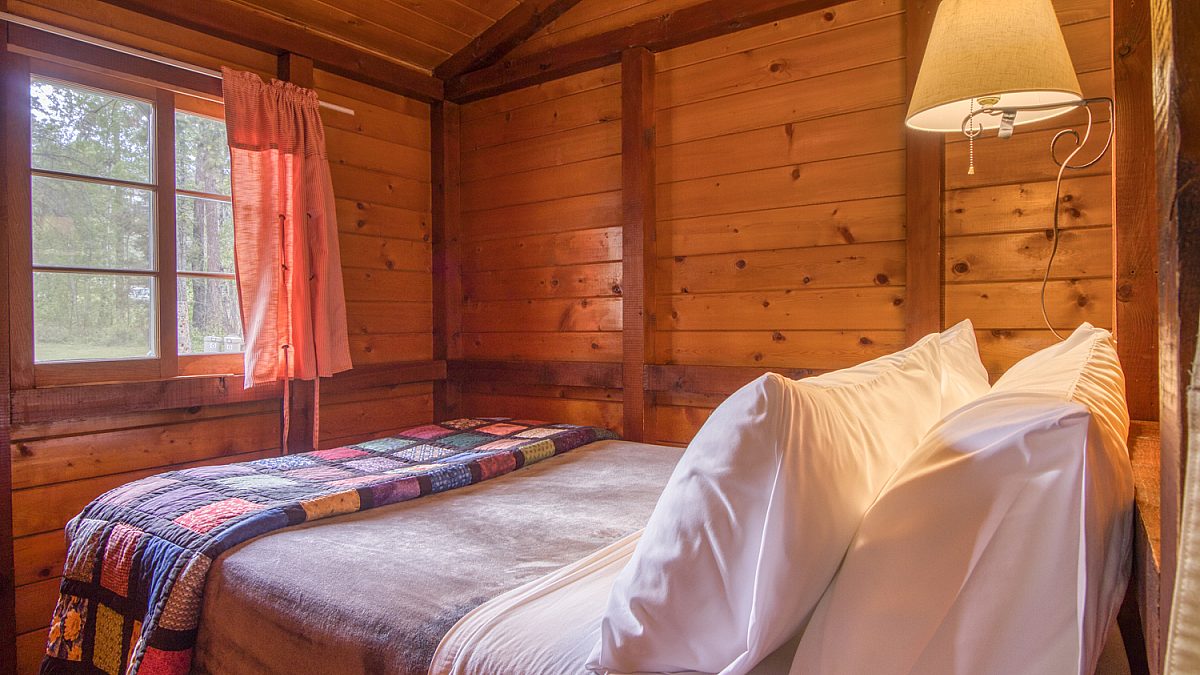 Double bed in wood panelled cabin bedroom.