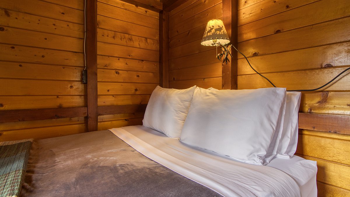 Double bed in wood panelled cabin bedroom.