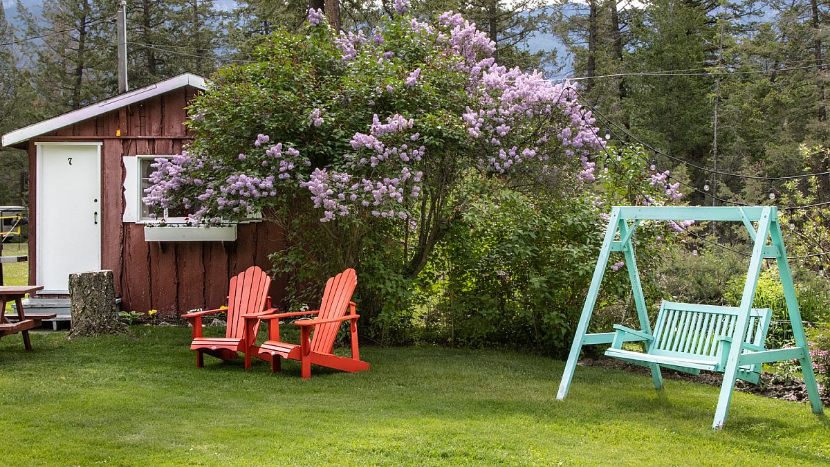 Outdoor living space with two red chairs and teal swing.