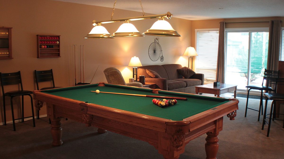 Recreation room with pool table, overhead lighting, seating area, and couch.