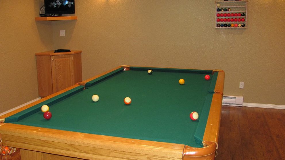 Pool table with balls in basement recreation area.