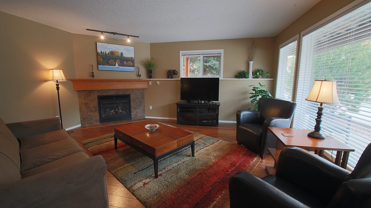Living room with fire place. Couch, leather chairs, coffee table, large rug and TV.
