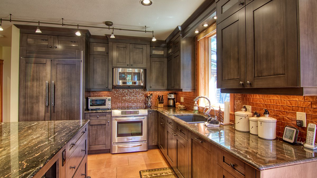 Large kitchen area with wide stretches of countertop, a stainless steel oven and appliances.