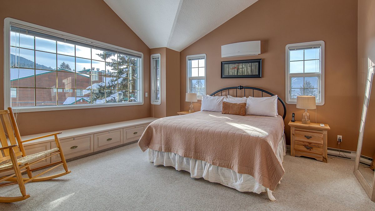 Master bedroom with king bed. Beige bedding and large window to the left.