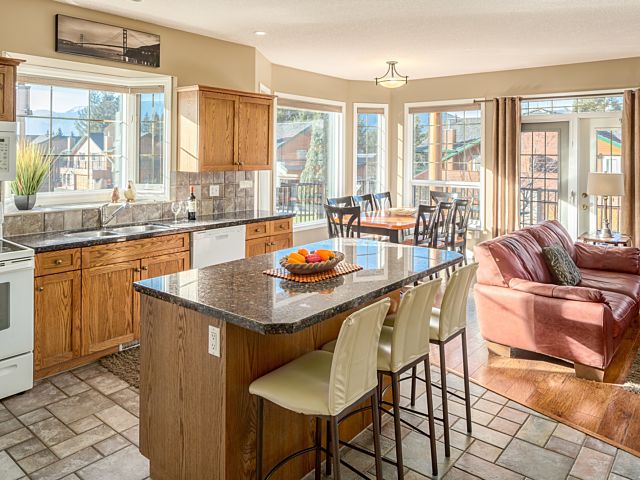 Kitchen with ample lighting and windows. Island with barstool seating. Living room to the left.