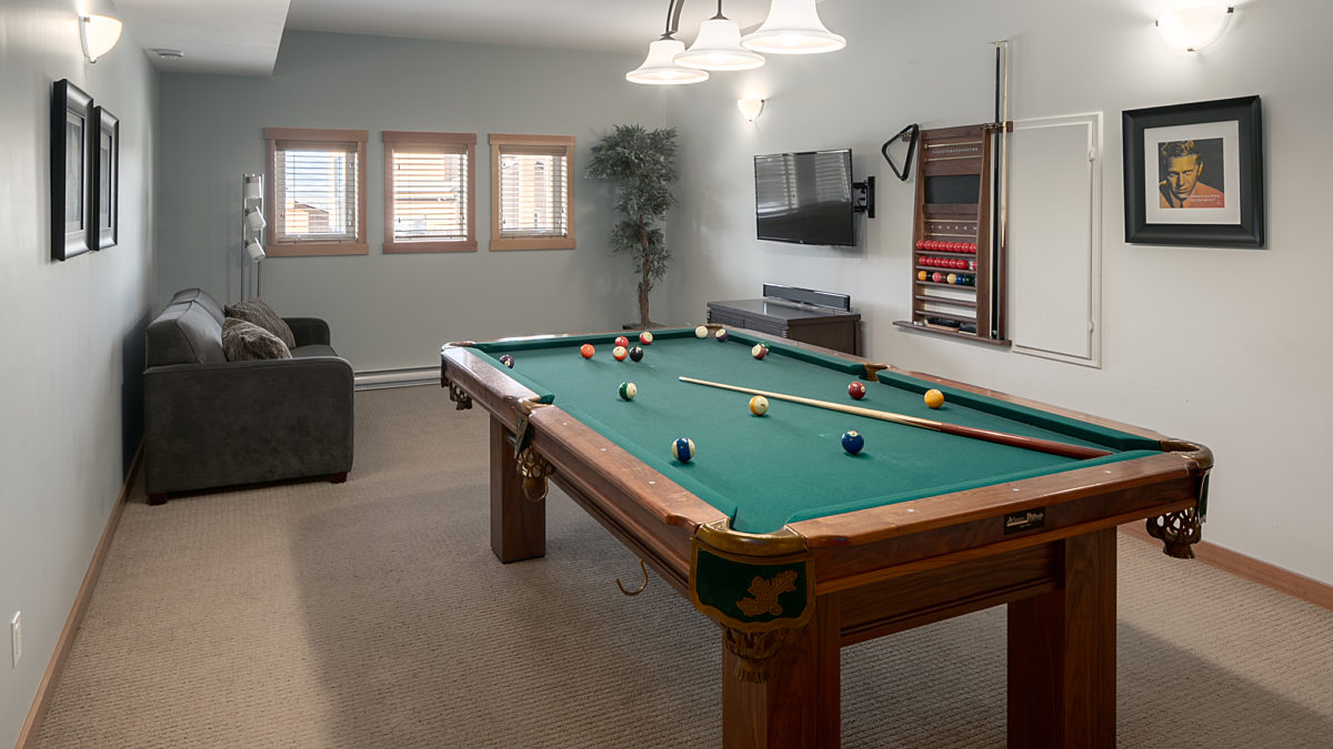 Recreation room with pool table, chairs, and windows to the rear.