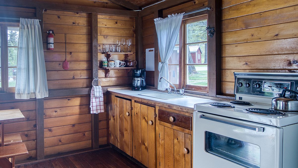 Kitchen space in wood panelled cabin with white appliances.