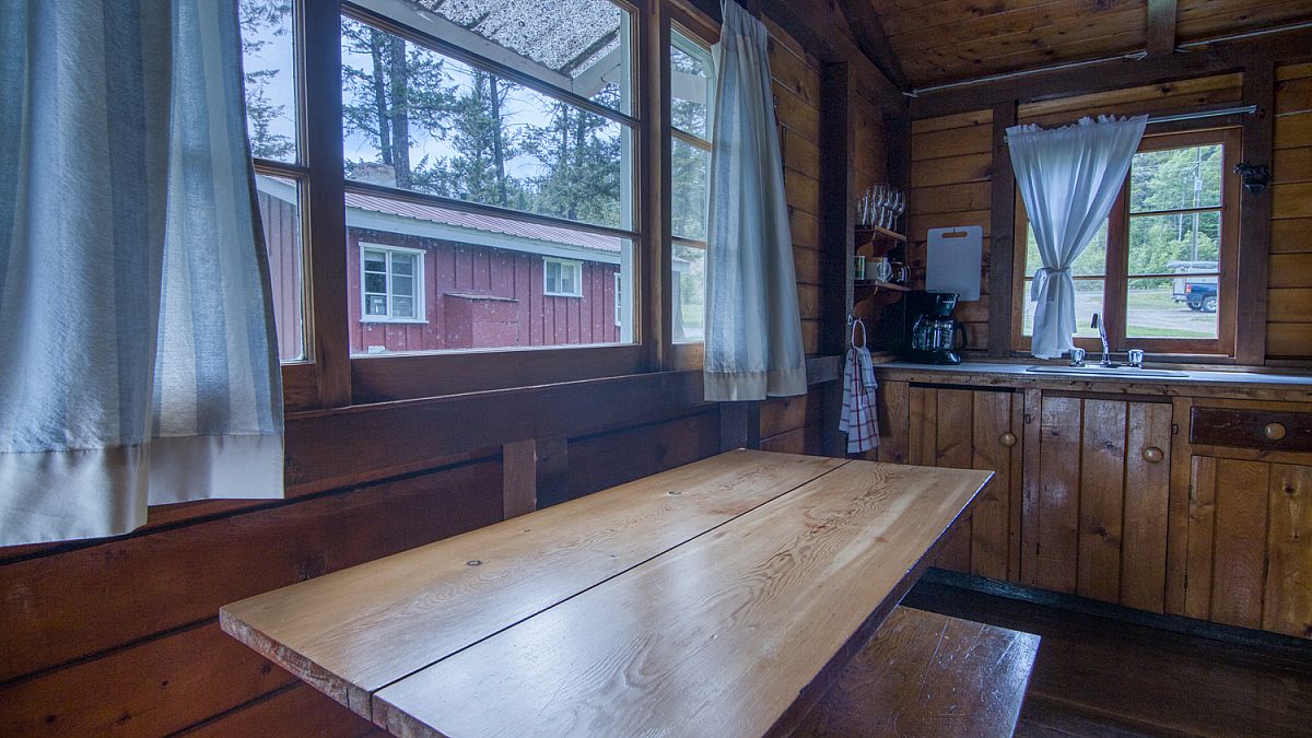 Dining area in wood panelled cabin. Picnic-style rustic table.