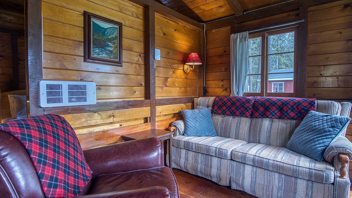Wood panelled cabin living room couch and leather chair, window to the right.